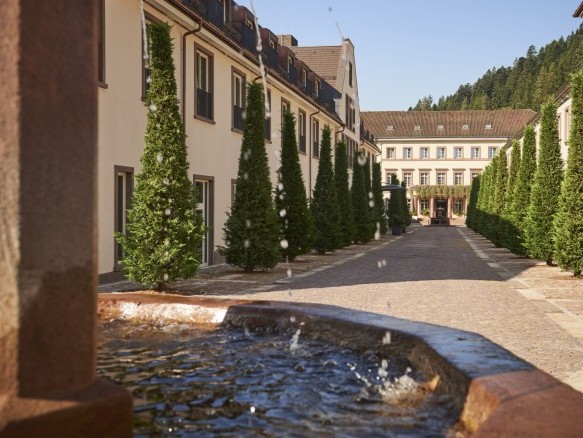 Blick auf den Hotelinnenhof mit Wasserbrunnen und symmetrischer Baumallee