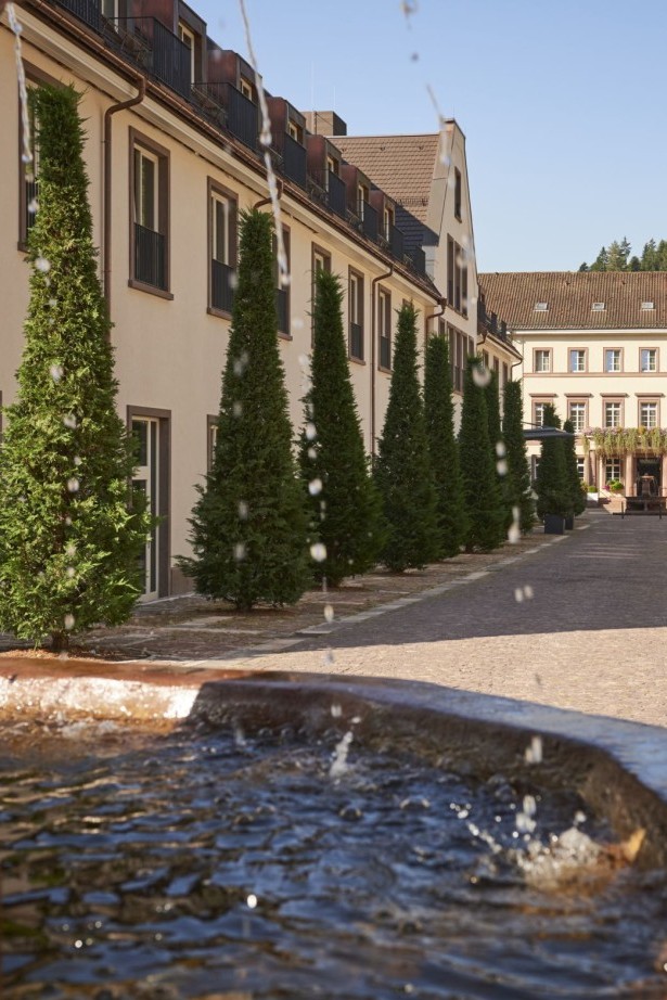 Blick auf den Hotelinnenhof mit Wasserbrunnen und symmetrischer Baumallee