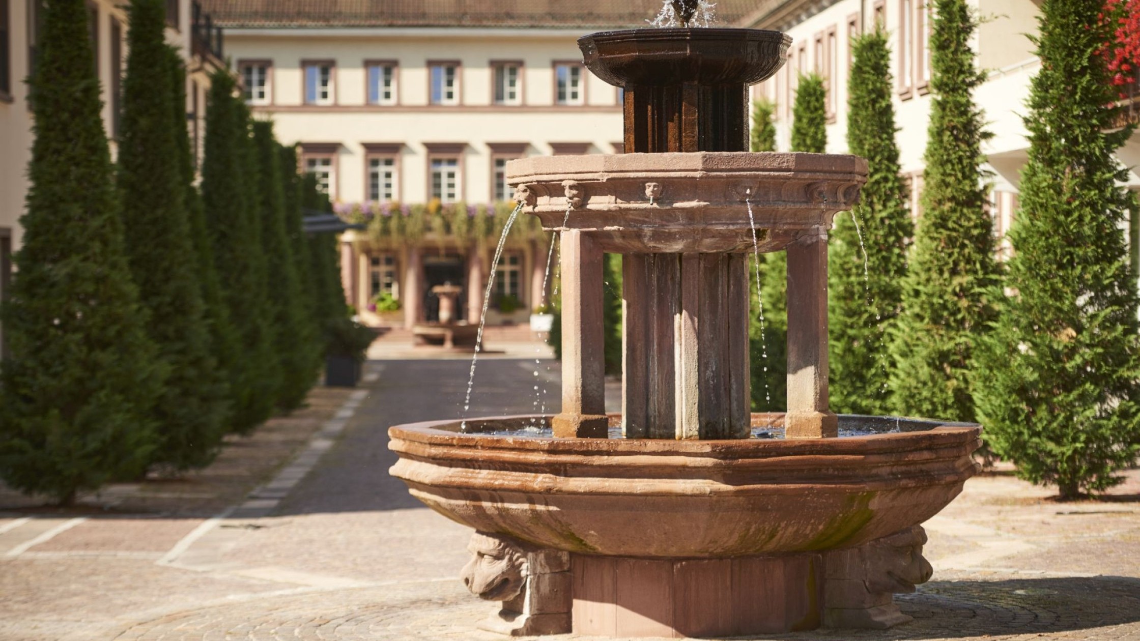 Blick durch Wasserspritzer des Brunnens auf die Hotelanlage