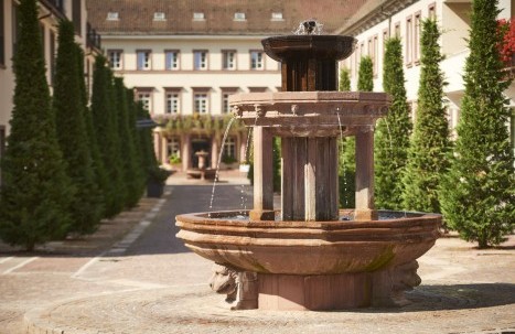 Blick durch Wasserspritzer des Brunnens auf die Hotelanlage