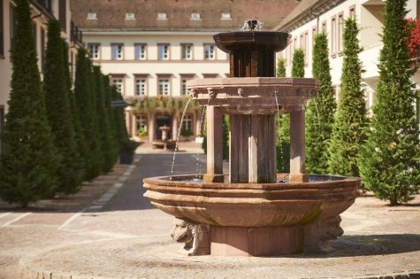 Blick durch Wasserspritzer des Brunnens auf die Hotelanlage