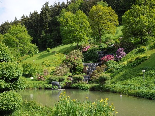 Idyllischer Hotelgarten mit Wasserfall und blühenden Büschen