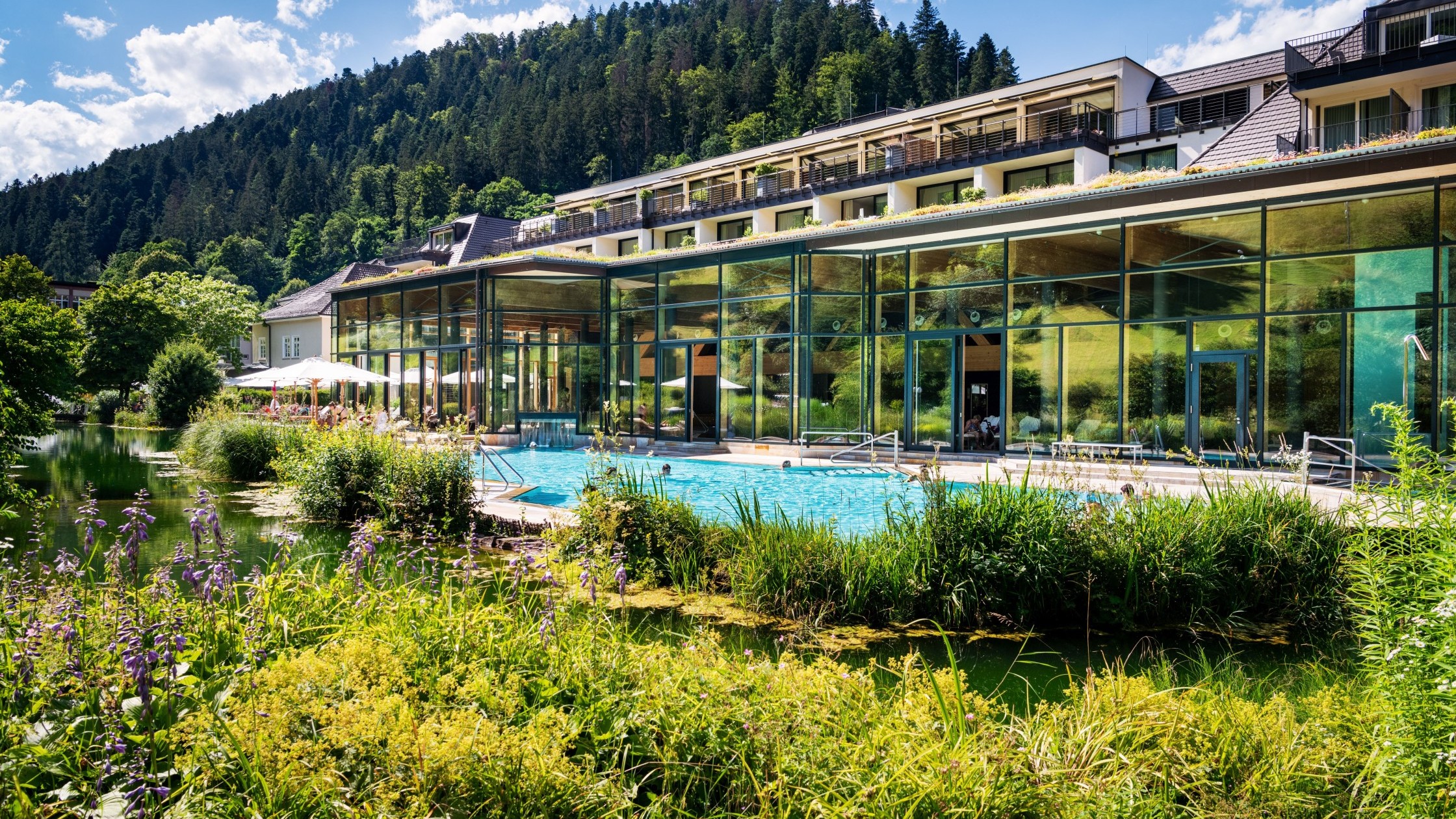 Außenansicht des Wellnesshotels Therme Bad Teinach mit Pool und Naturteich
