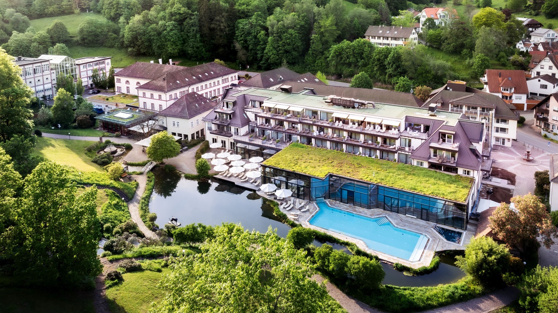 Luftansicht des Wellnesshotels Bad Teinach mit Pool, Liegeflächen und Teich