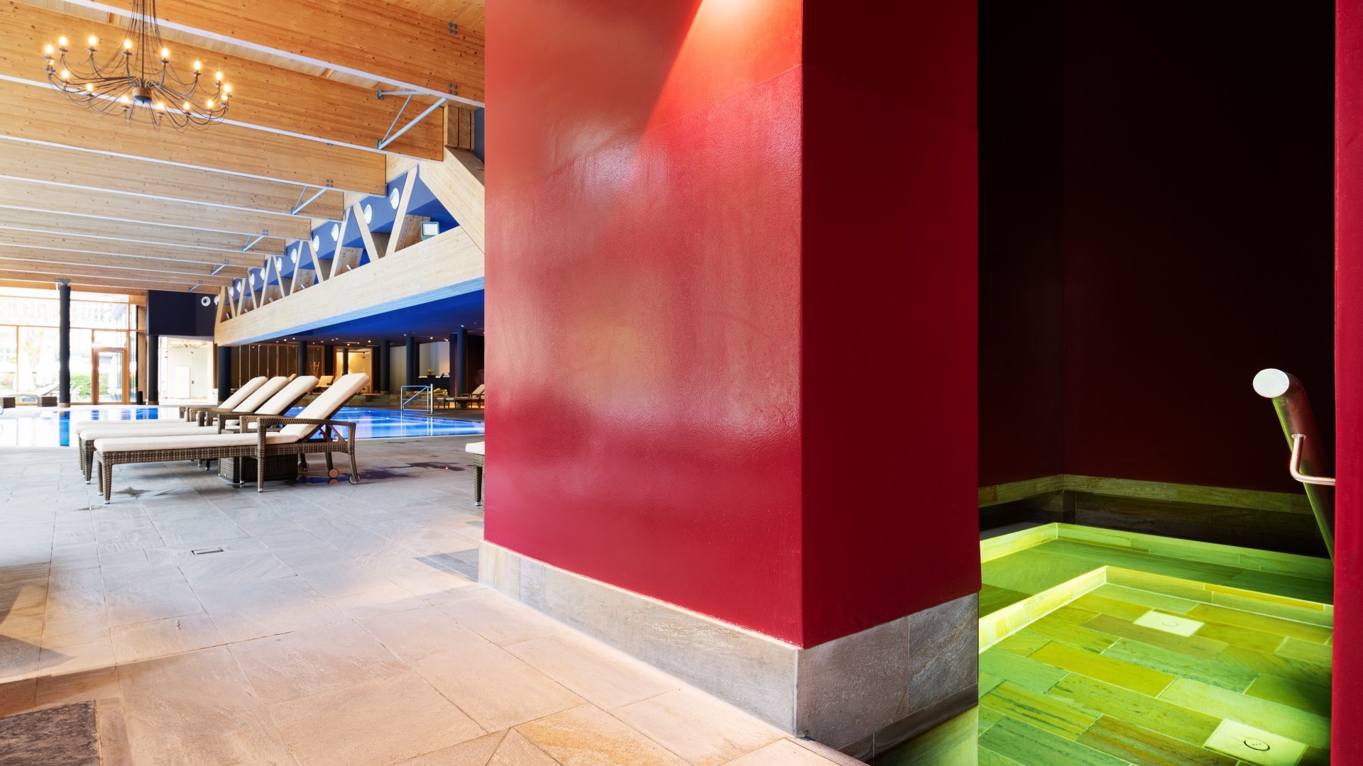 Moderner Wellnessbereich der Mineraltherme mit warm beleuchtetem Innenpool und stilvollen Liegen