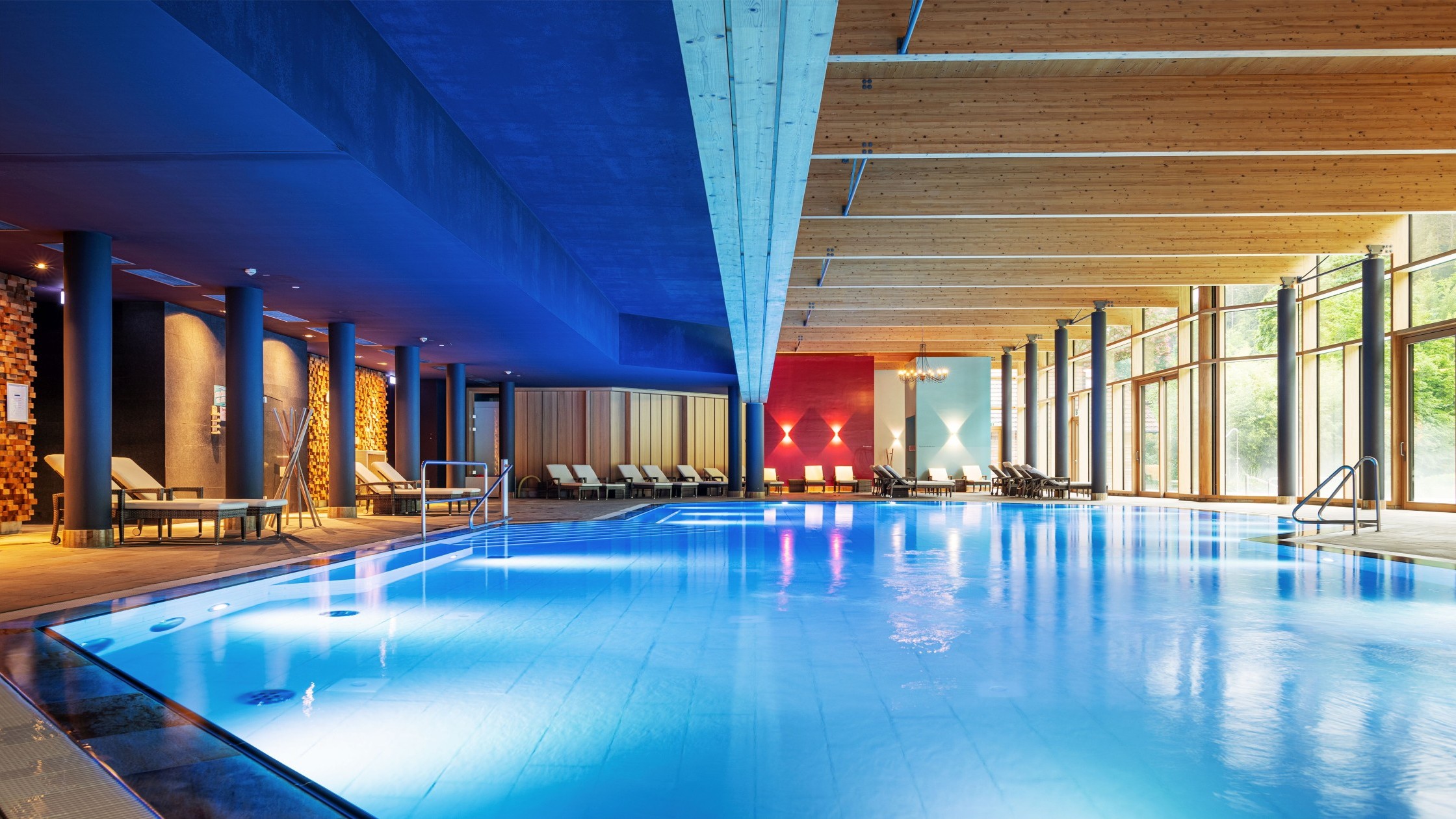 Mineraltherme mit großem Innenpool, Liegestühlen und modernem Lichtkonzept