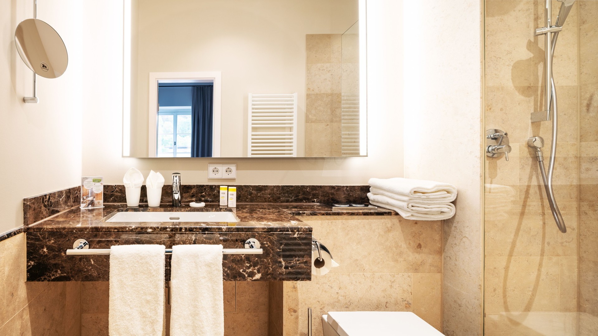 Modernes Badezimmer mit Marmorwaschtisch, Glasdusche und frischen Handtüchern