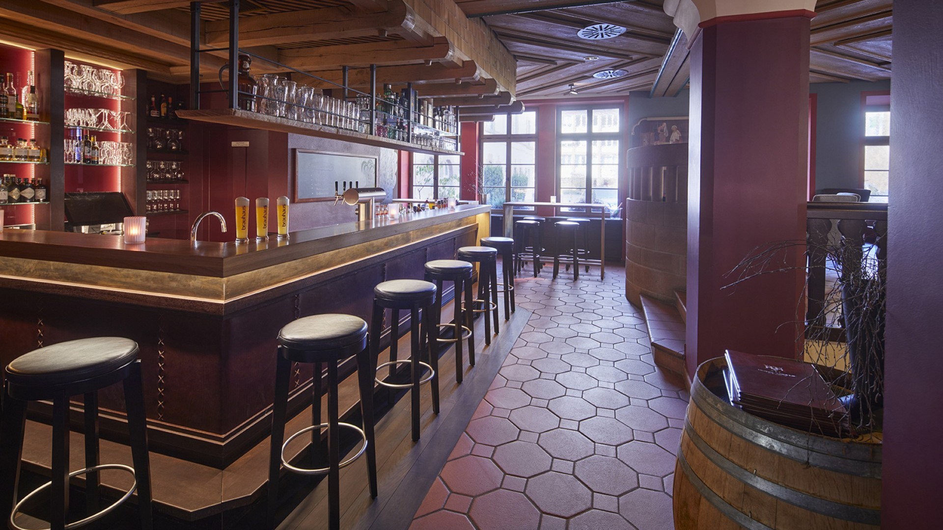 Stilvolle Hotelbar mit Holzdecke, Lederhockern und beleuchteten Regalen