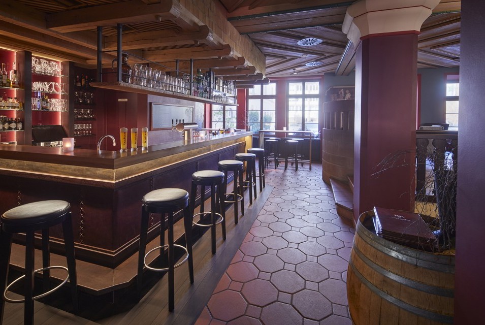 Stilvolle Hotelbar mit Holzdecke, Lederhockern und beleuchteten Regalen