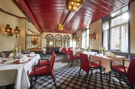 Stilvolles Hotelrestaurant mit roten Stühlen, weiß gedeckten Tischen und großen Fenstern