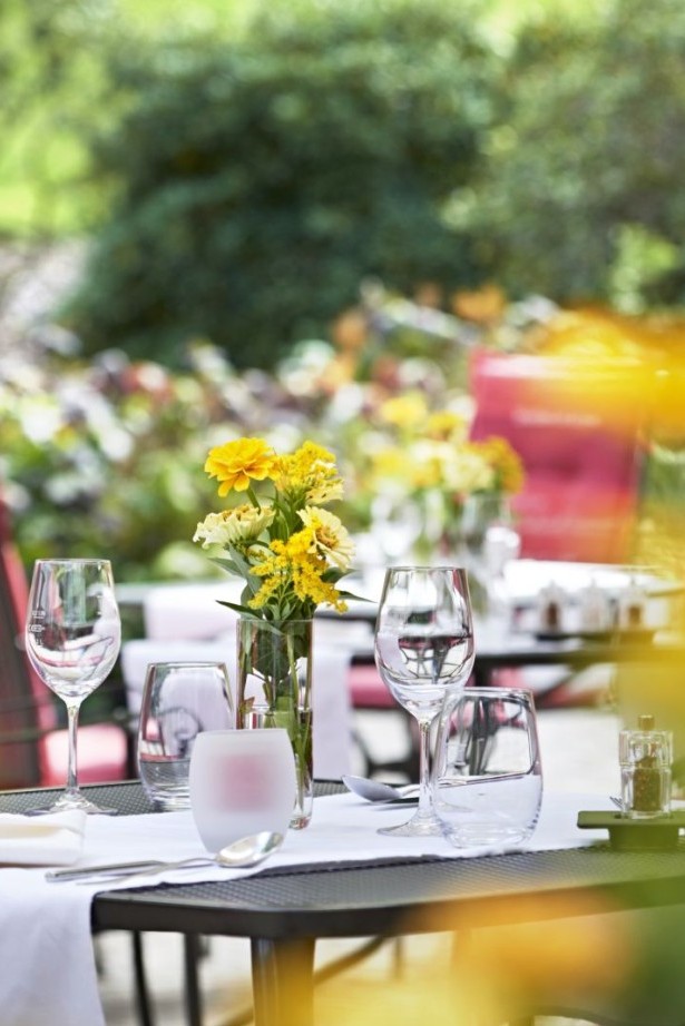 Detailaufnahme eines liebevoll gedeckten Terrassentisches mit gelben Blumen