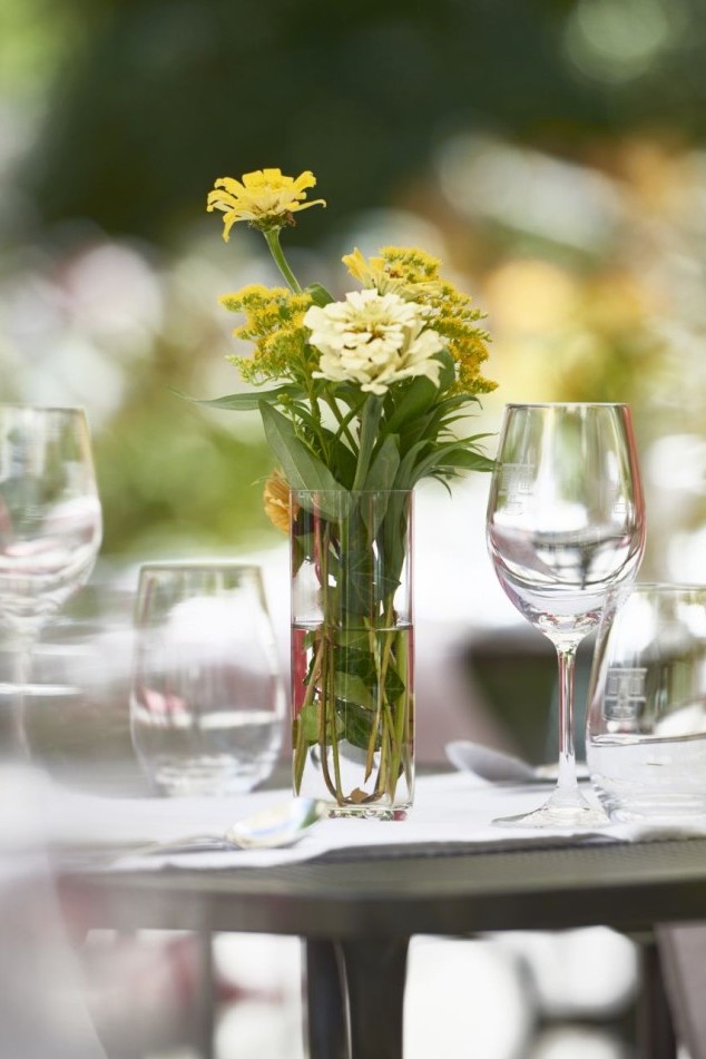 Nahaufnahme eines Glastisches mit Blumen und Gläsern