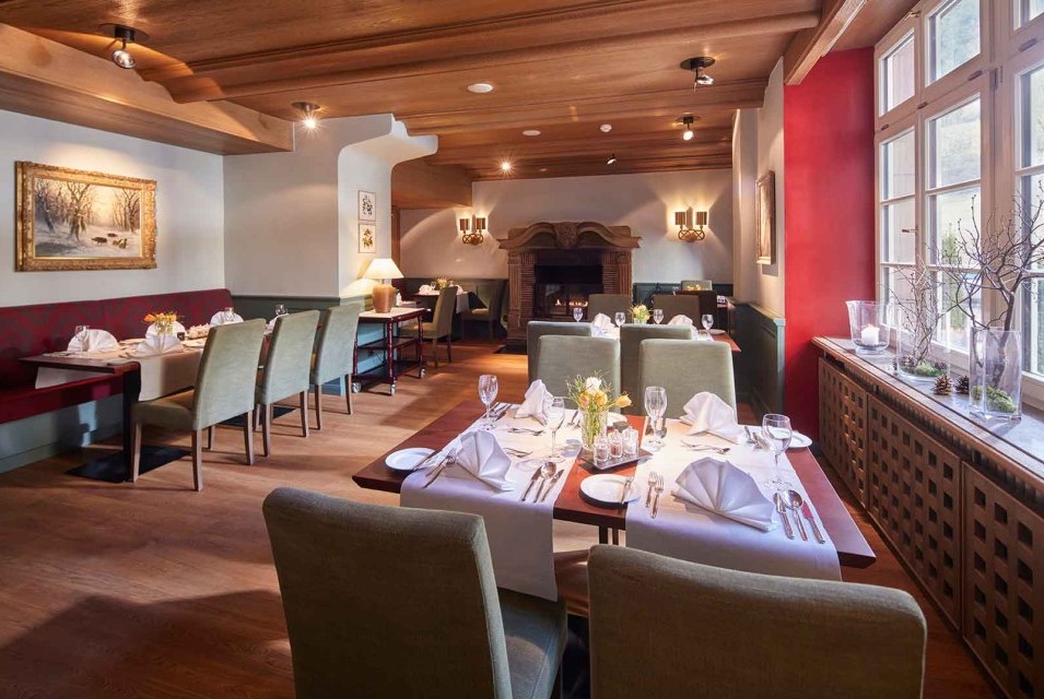 Stilvolles Restaurant mit gedeckten Tischen, Holzdecke und großen Fenstern