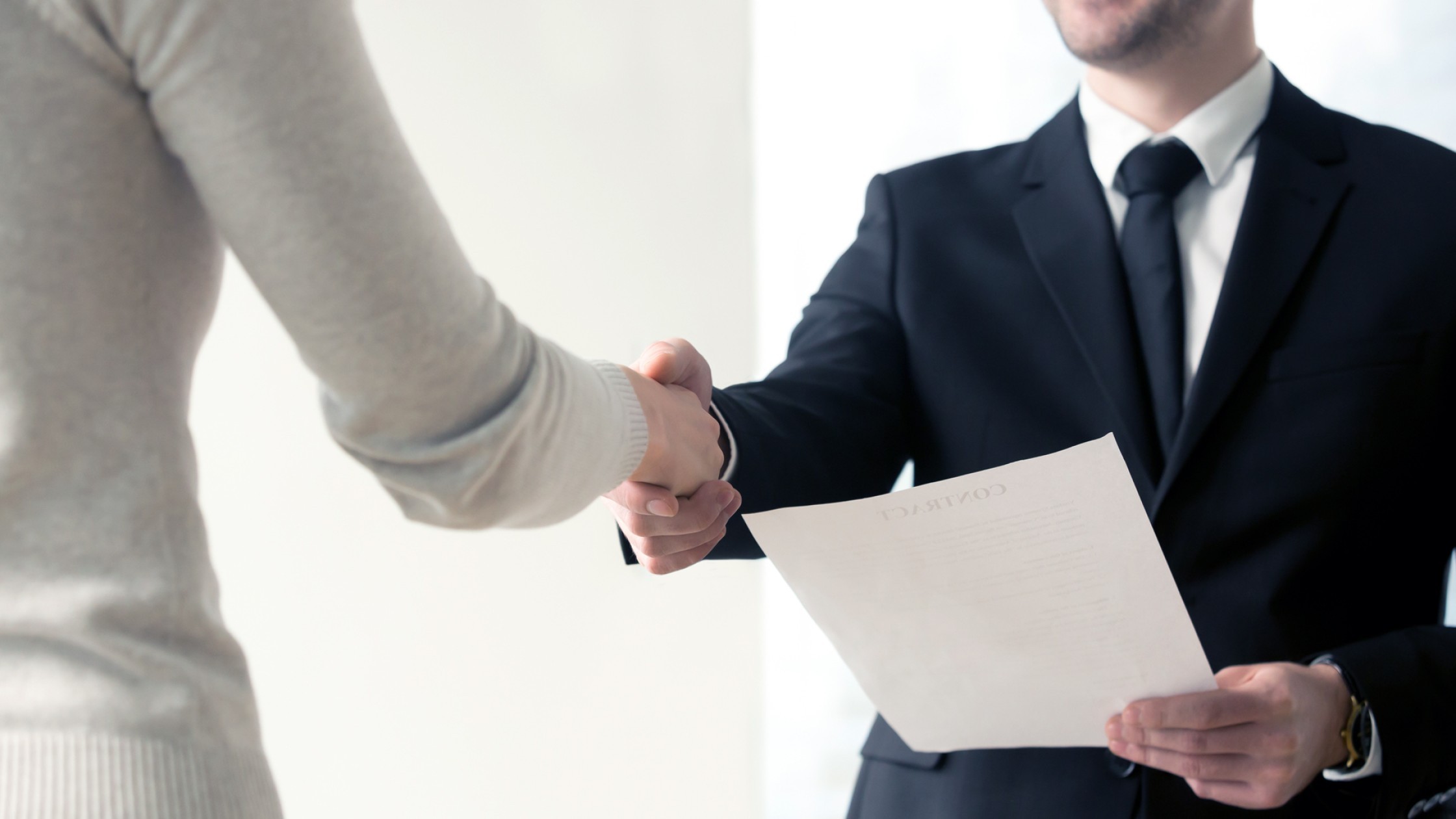 Handschlag zwischen zwei Personen beim Vertragsabschluss in einem professionellen Umfeld