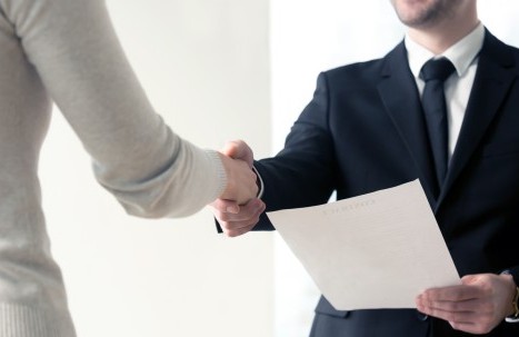 Handschlag zwischen zwei Personen beim Vertragsabschluss in einem professionellen Umfeld