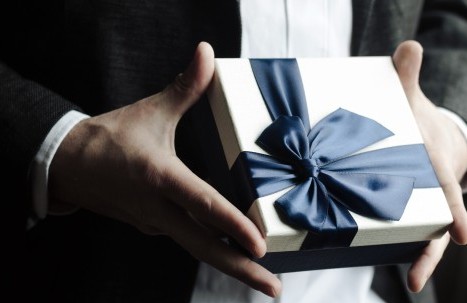 Stilvolle Geschenkbox mit dunkelblauer Schleife in eleganter Handhaltung