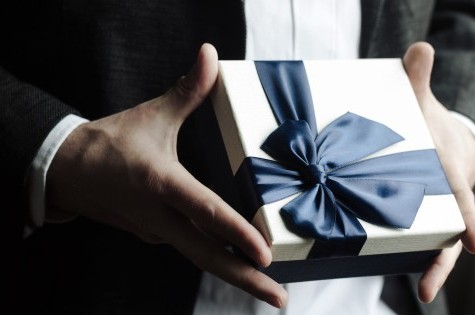 Stilvolle Geschenkbox mit dunkelblauer Schleife in eleganter Handhaltung