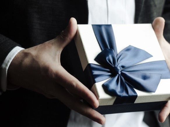 Stilvolle Geschenkbox mit dunkelblauer Schleife in eleganter Handhaltung