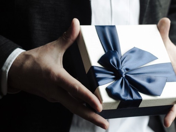 Stilvolle Geschenkbox mit dunkelblauer Schleife in eleganter Handhaltung