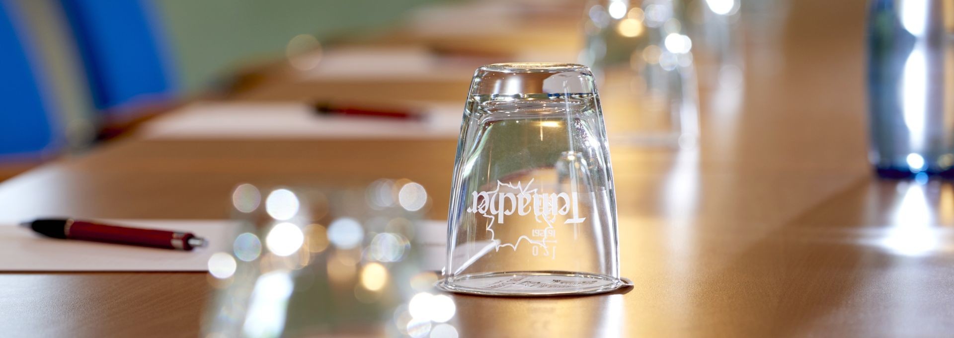 Nahaufnahme eines modernen Konferenztisches mit Gläsern, Stiften und Schreibblöcken für Business-Meetings