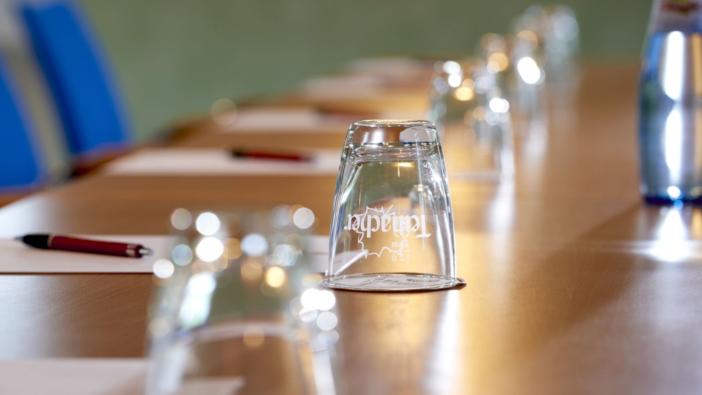 Nahaufnahme eines modernen Konferenztisches mit Gläsern, Stiften und Schreibblöcken für Business-Meetings