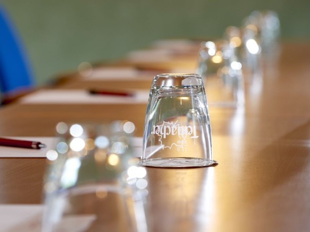 Nahaufnahme eines modernen Konferenztisches mit Gläsern, Stiften und Schreibblöcken für Business-Meetings