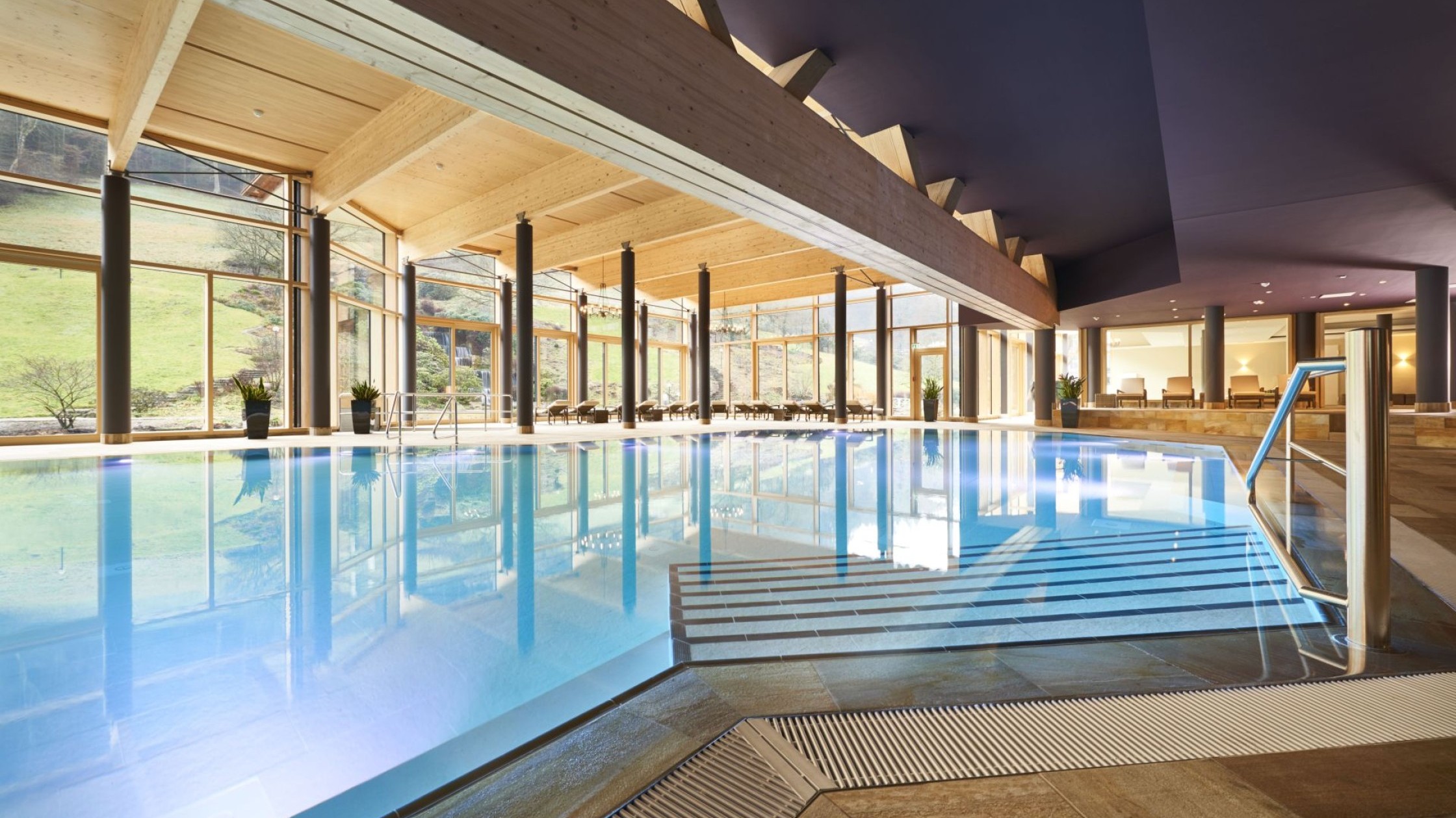 Großzügiger Innenpool mit bodentiefen Fenstern und Blick ins Grüne