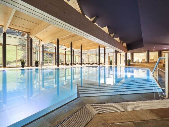 Großzügiger Innenpool mit bodentiefen Fenstern und Blick ins Grüne