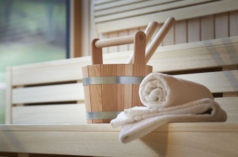 Saunaaufgusskübel mit Handtuch auf heller Holzbank