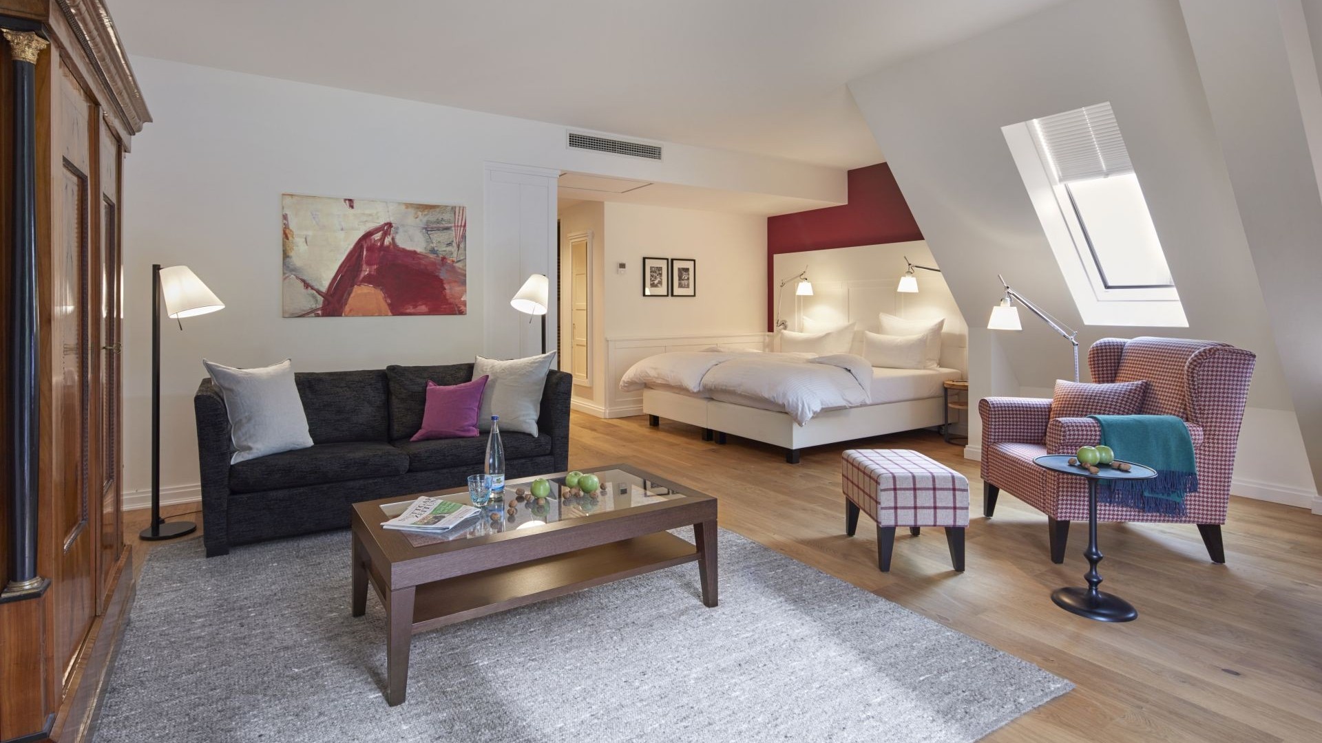 Geräumiges Zimmer mit gemütlichem Sessel, Sofa und modernem Bett