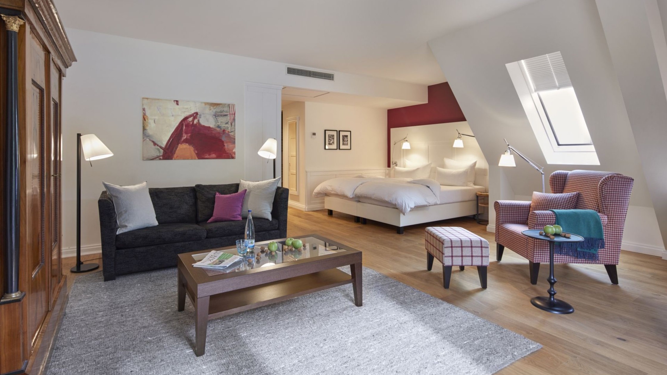 Geräumiges Zimmer mit gemütlichem Sessel, Sofa und modernem Bett