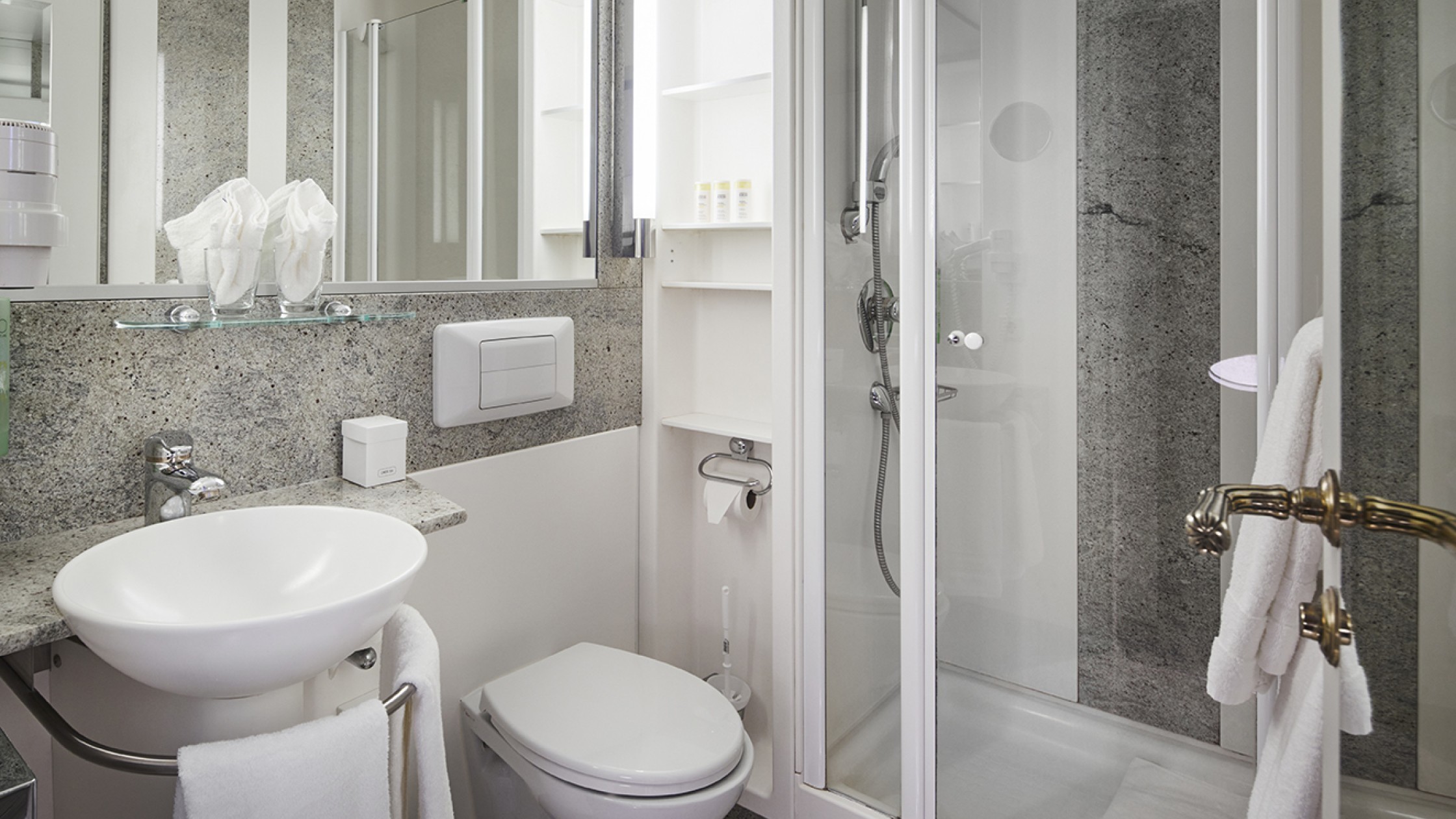 Kompaktes Bad mit Glasdusche, Waschbecken und grauem Naturstein-Design