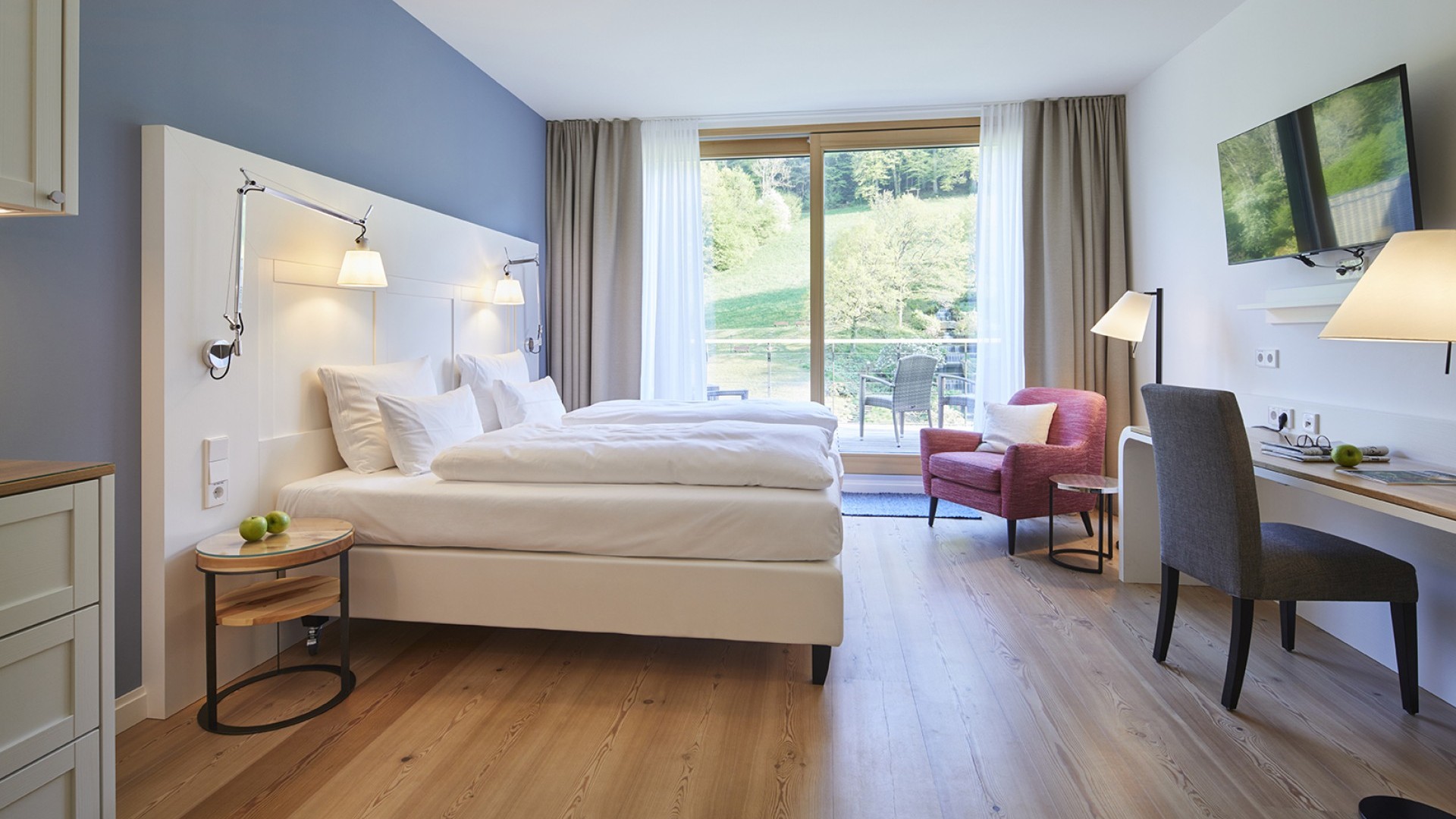 Modernes Hotelzimmer mit Balkon und Blick auf grüne Hügel