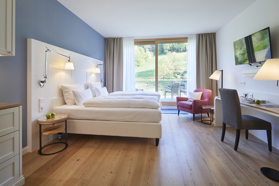 Modernes Hotelzimmer mit Balkon und Blick auf grüne Hügel