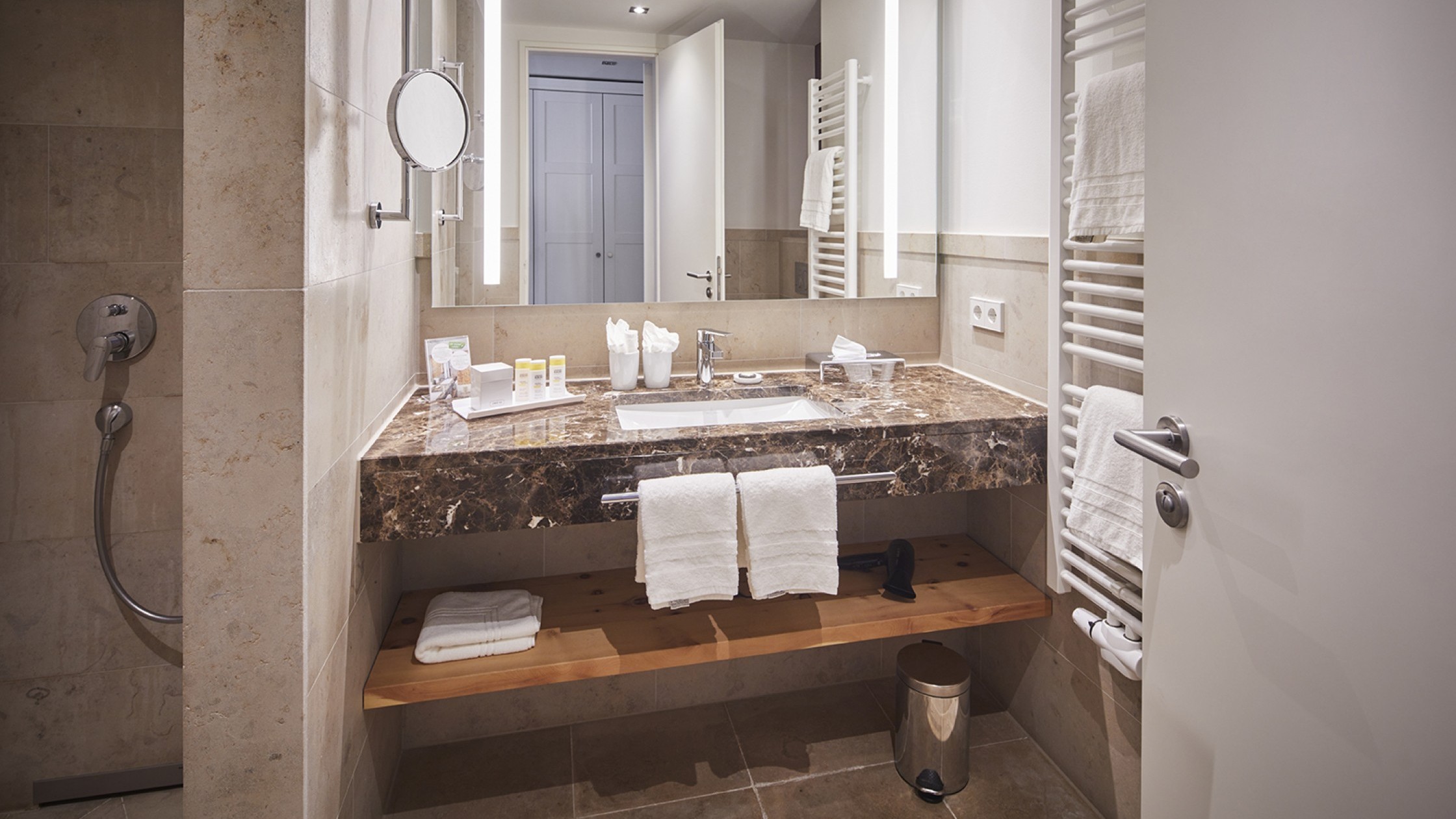 Stilvolles Hotelbad mit großem Spiegel und Marmorwaschtisch