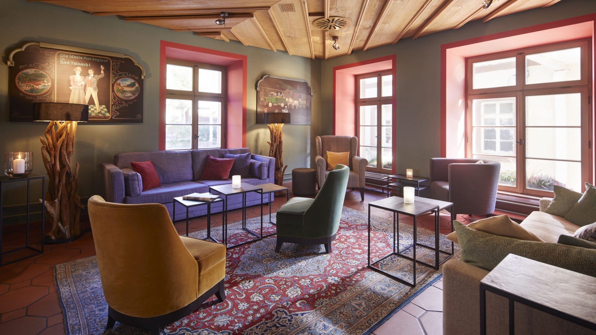 Hotelbar mit Teppich, farbigen Sesseln, Sofas und Kerzen auf Beistelltischen