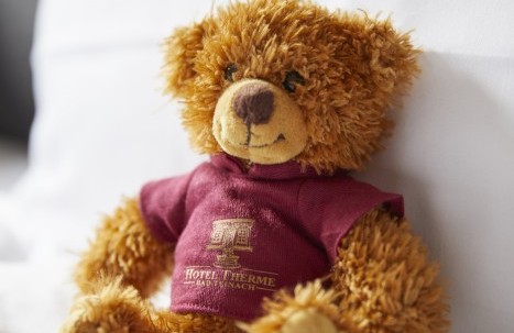 Kuscheliger Hotelteddy auf frischem Bettbezug