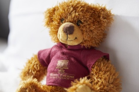 Kuscheliger Hotelteddy auf frischem Bettbezug