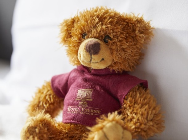 Kuscheliger Hotelteddy auf frischem Bettbezug